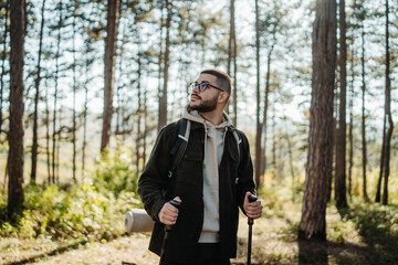 Young caucasian man hiking or trekking through the forest	