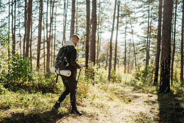 Young caucasian man hiking or trekking through the forest	