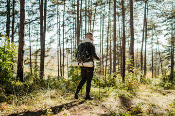 Obraz premium Young caucasian man hiking or trekking through the forest 
