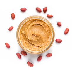 Open jar of peanut butter and scattered peanuts on white background, top view. Unhealthy spread...