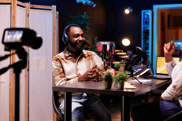 African American man creates vlogs using digital camera while producing podcasts with professional...