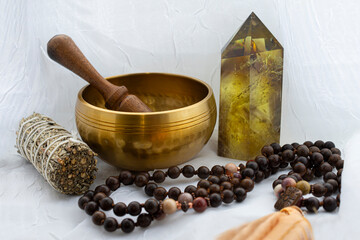 An image of a meditation singing bowl with white sage and citrine crystal tower on a transparent white lace background. 