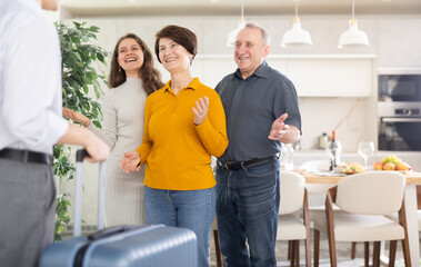 Naklejka premium Happy parents and daughter joyfully greet their son and brother, who came from far away