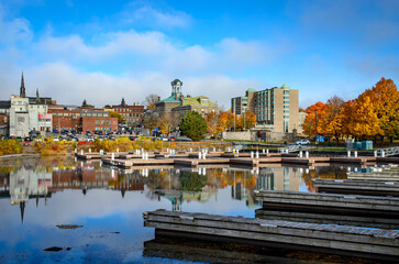 View from the empty marina harbour showing Brockville's city hall and downtown buildings with trees...