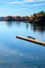 Obraz premium Single small boat moored at a pier on the St. Lawrence River with islands in the background with fall leaves.