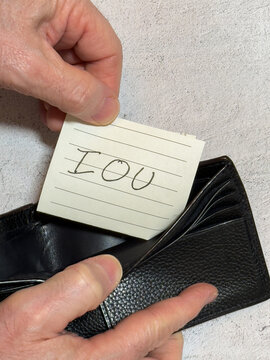 Hands holding an IOU note in a wallet.