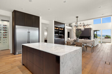 Kitchen with Waterfall Island in New Modern Luxury Home. Shows View of Dining and Living Room