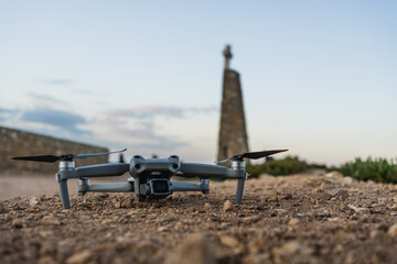 Drone rests on ground near historic monument at sunset in rural area