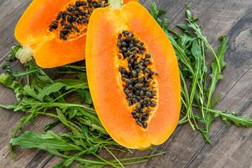 Papaya fruit and rucola on a dark wooden background. Slices of sweet papaya and rucola