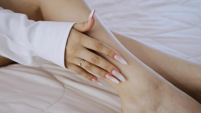 The girl gently runs her fingers over her leg. She strokes herself from the bottom up. The camera is watching her hand