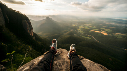 A person relaxes on a rock, overlooking a breathtaking mountain view at sunset.