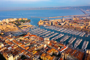 Obraz premium Picturesque drone view of modern Marseille cityscape on Mediterranean coast overlooking large Old Port with moored pleasure yachts on sunny day, France