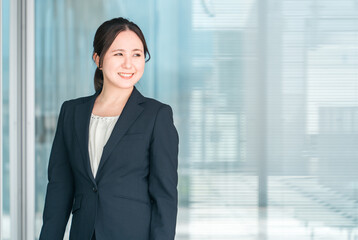 オフィスビルの前にいるスーツ姿の若いアジア人ビジネスウーマン
