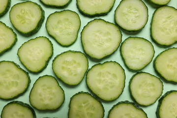 Slices of fresh cucumbers on turquoise background, flat lay