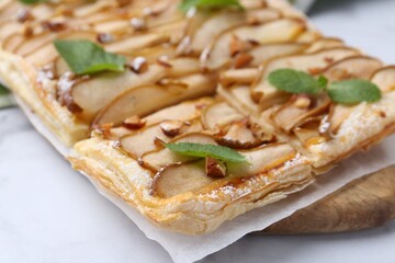 Tasty puff pastry pie with pears and mint on white table, closeup