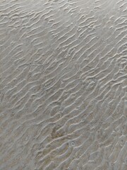 The texture of wet sand on the beach with a wave pattern is suitable for background illustrations