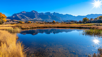 serene travel scene of tranquil lake surrounded by mountains and golden grass under clear blue sky. reflection in water enhances peaceful atmosphere