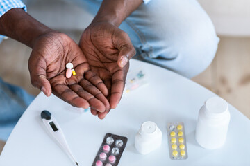 Coronavirus therapy concept. Closeup of African american man holding drugs indoors, top view. Empty space