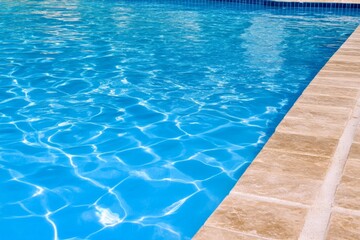 A close-up of tiny air bubbles rising in an aqua-colored pool, with the water appearing crystal clear