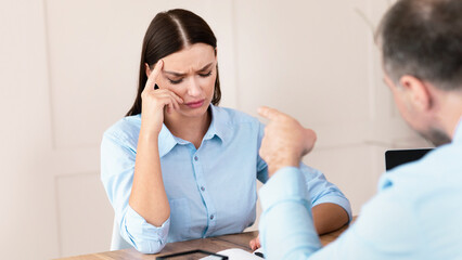 Sexism At Work. Boss Shouting At Office Worker Girl Threatening Her To Be Fired Sitting At Workplace. Selective Focus