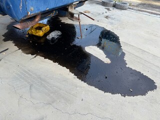 Car Trouble: A puddle of black oil spills out from under a car, a stark reminder of unexpected...