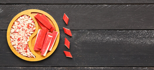 Plate with tasty crab sticks on dark wooden background © Pixel-Shot