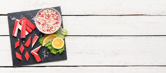 Slate board with tasty crab sticks on light wooden background © Pixel-Shot