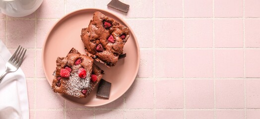 Plate with pieces of raspberry brownie on pink background with space for text, top view
