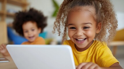 Two cheerful children engaged with a digital tablet, surrounded by classmates in a lively classroom environment, highlighting the joy of education.