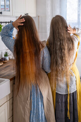Fototapeta premium mother and daughter with long hair, dressed in vintage dresses, stand side by side, symbolizing family bond, carefree moment between mother and daughter, Two generations, bonded by love
