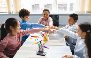 Teamwok And Children Concept. Diverse excited group of emotional happy junior school kids sitting...