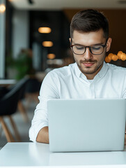 young man in white shirt works intently on laptop in bright, contemporary office space. modern design and focus on productivity create inspiring atmosphere