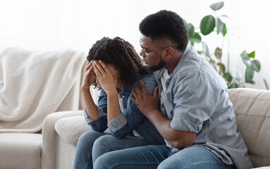 Dependent Relationship Concept. Young Black Guy Soothing His Depressed Girlfriend At Home,...