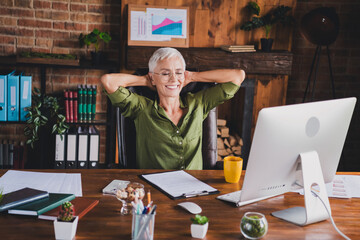 Photo of charming attractive lady dressed shirt eyewear hold arms behind head sit workplace...