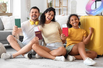 Happy family with passports and packed suitcase for travel sitting on floor at home