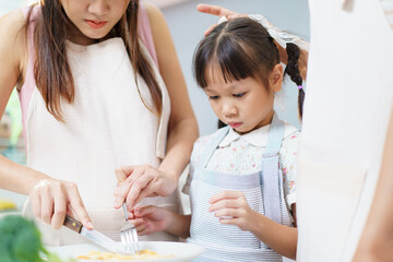 Happy cheerful Asian family with farther, mother, and daughter are enjoy making and having a breakfast together in kitchen. A pregnant woman make a breakfast with husband and daughter in kitchen.