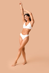 Beautiful young happy body positive woman in underwear on beige background