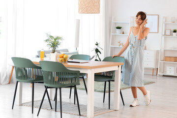 Young woman with headphones listening to music in dining room