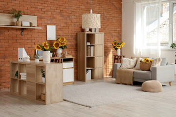Interior of stylish living room with grey sofa and beautiful sunflowers