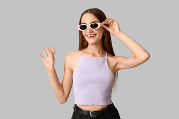 Happy young woman in stylish sunglasses on grey background