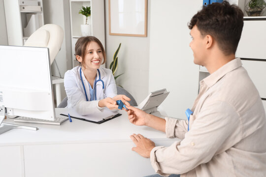 Female doctor and male patient with blue ribbon in clinic. Prostate cancer awareness concept