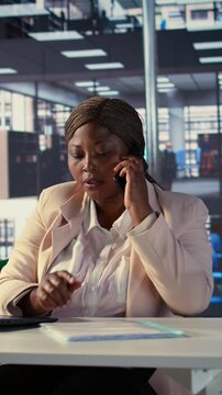 Vertical Video African american general manager answers smartphone call to discuss performance metrics, focusing on business development project. Director multitasking daily operations and analytics