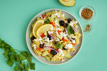 Plate with traditional pasta salad on turquoise background