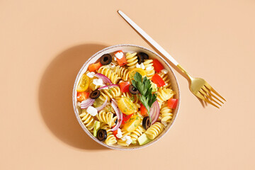 Plate with traditional pasta salad on beige background
