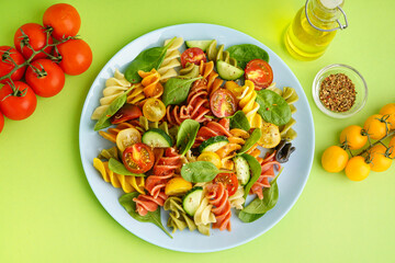 Plate with Italian pasta salad on green background