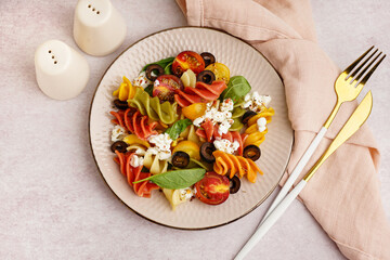 Plate with Italian pasta salad on light background