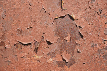 An ancient and weathered red surface exhibiting flaking paint and a rich texture throughout