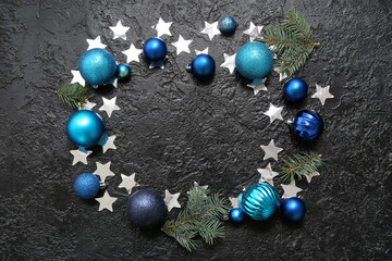 Frame made of Christmas balls, fir tree branches and confetti on black background