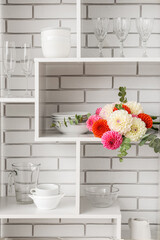 Bouquet of beautiful dahlia flowers on shelf against light brick wall