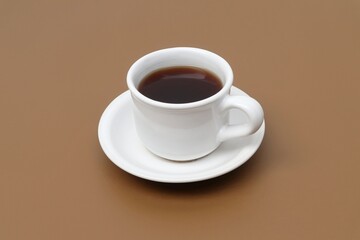 Black coffee in a white cup on a brown table